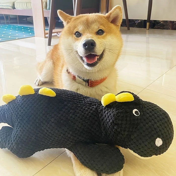 Dog playing with a toy alligator on a tiled floor